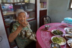 陳瑞光百歲母親從社區鄰長徐雲嬌手中接獲熱騰騰肉粽
