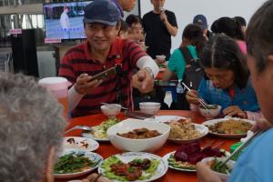中午供餐推出東片村社區風味餐，燉煮多時的傳統客家爌肉、香蕉飯，參加群眾吃得津津有味